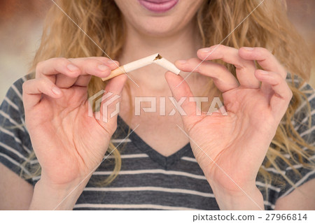 Composite image of woman snapping a cigarette over white background 27966814