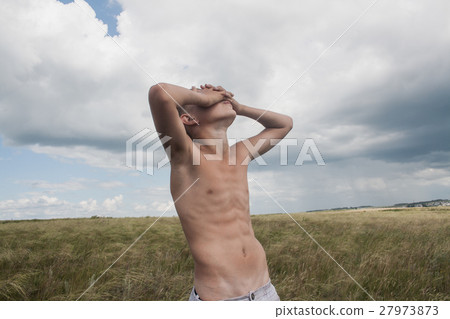 young boy stands in a field. boy in shorts. 27973873