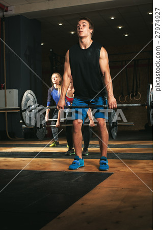 Three adults exercising with barbells in gym Three adults exercising with barbells in gym 27974927