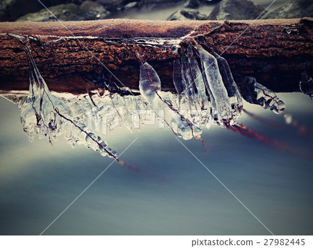 Long icicle hang above dark freeze water of stream Long icicle hang above dark freeze water of stream 27982445