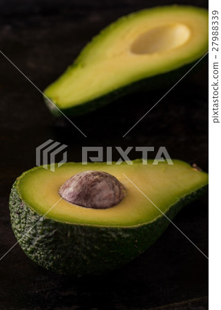 Single avocado severed in half on dark tray Single avocado severed in half on dark tray 27988339