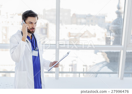 Serious male doctor communicating on phone Serious male doctor communicating on phone 27996476