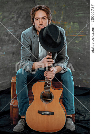 Cool guy sitting with guitar on gray background 28005787