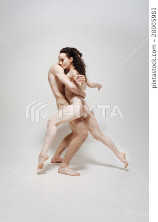 Muscular young athletes posing against white Muscular young athletes posing against white 28005981