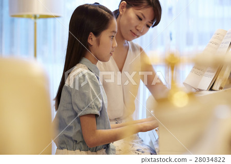 A girl who receives a piano lesson 28034822