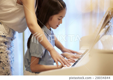 A girl who receives a piano lesson A girl who receives a piano lesson 28034844