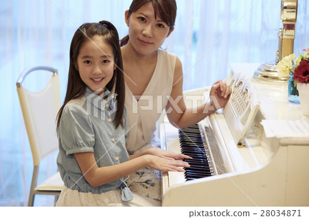A girl who receives a piano lesson 28034871