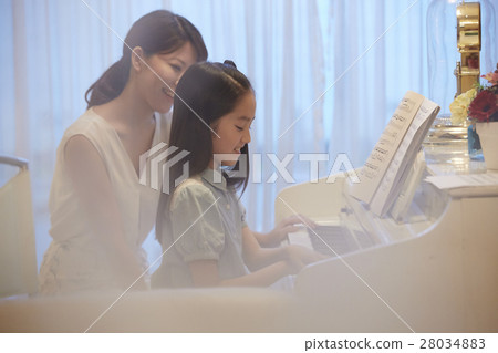 A girl who receives a piano lesson 28034883