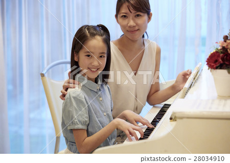 A girl who receives a piano lesson 28034910