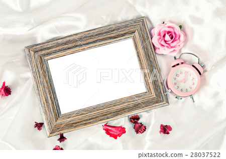 Blank wooden photo frame and pink alarm clock. 28037522