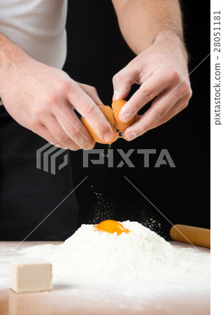 Man breaking egg on flour 28051181