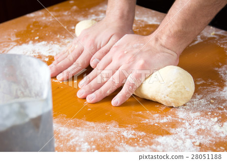 Man kneading dough on flour covered table 28051188