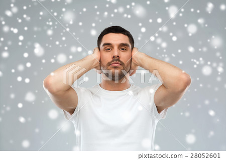 young man covering his ears with hands over snow 28052601