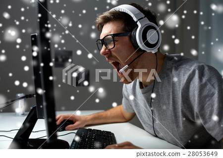 man in headset playing computer video game at home man in headset playing computer video game at home 28053649