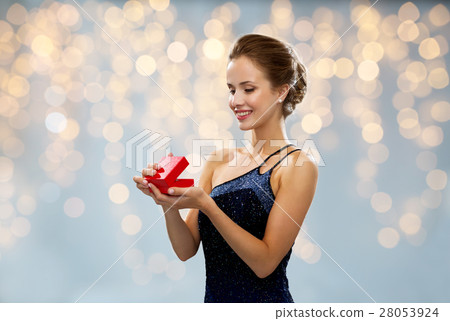 smiling woman holding red gift box over lights smiling woman holding red gift box over lights 28053924