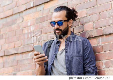 man with backpack texting on smartphone in city man with backpack texting on smartphone in city 28054058