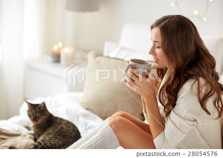happy woman with cup of coffee in bed at home 28054576