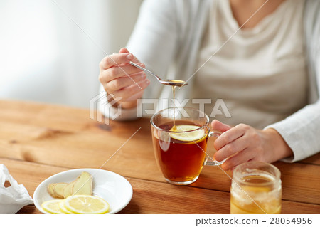 close up of ill woman drinking tea with lemon close up of ill woman drinking tea with lemon 28054956