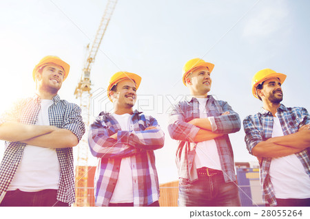 group of smiling builders in hardhats outdoors 28055264