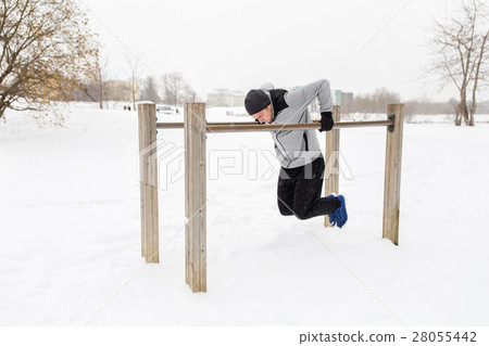 young man exercising on parallel bars in winter 28055442