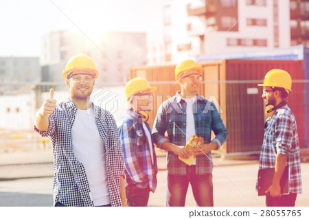 group of smiling builders in hardhats outdoors group of smiling builders in hardhats outdoors 28055765