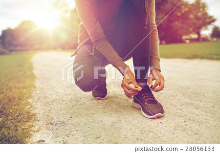 close up of woman tying shoelaces outdoors close up of woman tying shoelaces outdoors 28056133