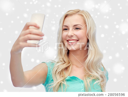 smiling young woman taking selfie with smartphone 28056596