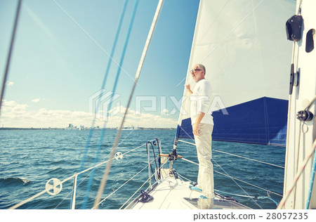 senior man on sail boat or yacht sailing in sea 28057235