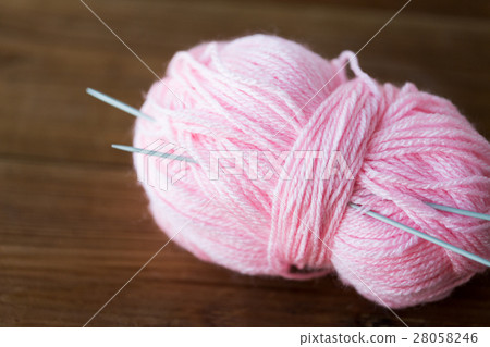 knitting needles and ball of pink yarn on wood knitting needles and ball of pink yarn on wood 28058246