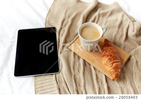 tablet pc, coffee and croissant on bed at home tablet pc, coffee and croissant on bed at home 28058403