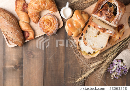 Mix baked bread and wheat on wood table background Mix baked bread and wheat on wood table background 28063258