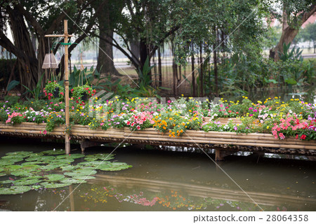 Beautiful flower garden with bamboo path over pond 28064358