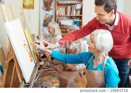 Delighted artist helping elderly woman in painting Delighted artist helping elderly woman in painting 28065758