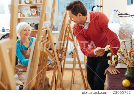 Happy artist pointing at flowers in painting Happy artist pointing at flowers in painting 28065792