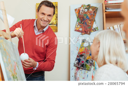 Smiling man teaching people in painting studio. Smiling man teaching people in painting studio. 28065794
