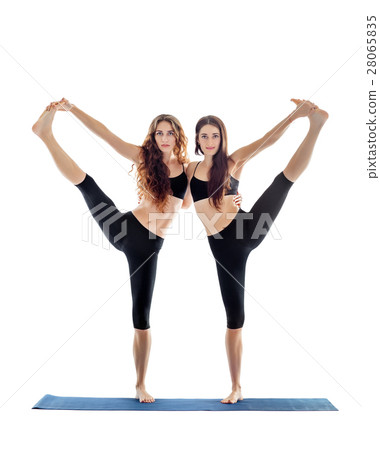 Two young women doing yoga asana extended hand to big toe pose. 28065835