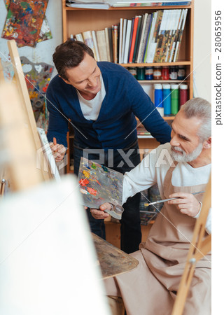Smiling artist helping elderly man in painting Smiling artist helping elderly man in painting 28065956