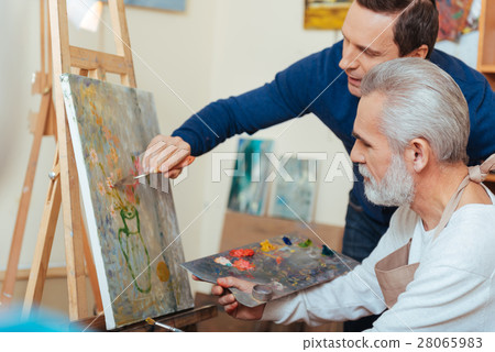 Young artist helping elderly man in painting 28065983