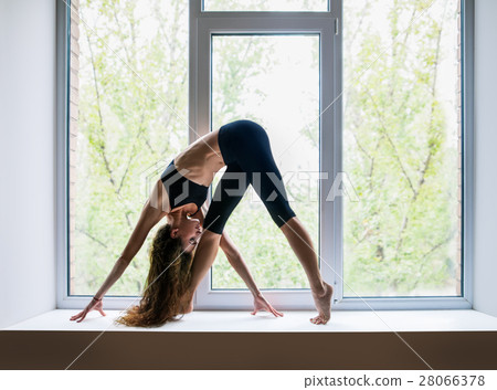 Beautiful woman doing yoga asana on window sill 28066378