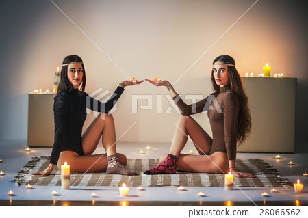 Two young women relax on plaid and holding candles in hands 28066562