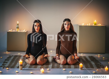 Two young women doing yoga asana diamond pose with candles in ha Two young women doing yoga asana diamond pose with candles in ha 28066563