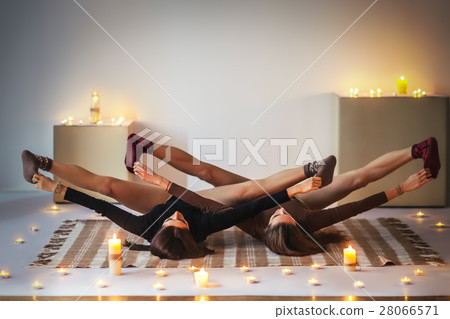 Two young women doing yoga asana upward angle open pose on plaid 28066571