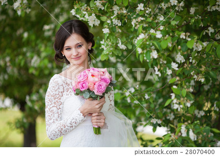 Beautiful bride with wedding bouquet in garden Beautiful bride with wedding bouquet in garden 28070400