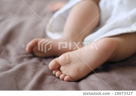 蹣跚學步的小可愛的腳在棕色的床床上打n 蹣跚學步的小可愛的腳在棕色的床床上打n 28073327