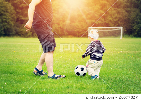Little boy playing football on the field with 28077827
