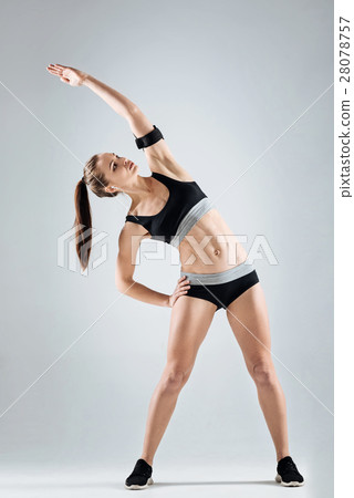 Motivated girl doing exercises on a grey Motivated girl doing exercises on a grey 28078757