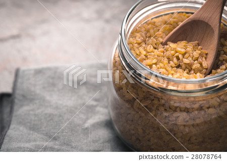Grain bulgur in a glass jar and in spoon close-up 28078764