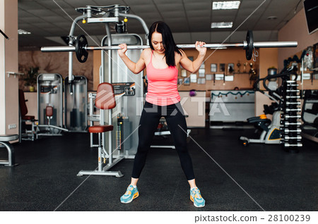 Beautiful fitness woman lifting barbell. 28100239
