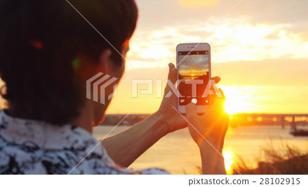 Young man taking photo using mobile phone of 28102915