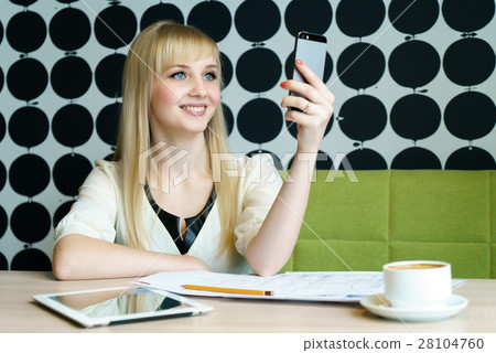 Girl sitting in cafe holds a smartphone 28104760